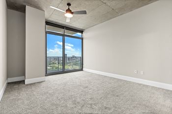 an empty living room with a ceiling fan and a window